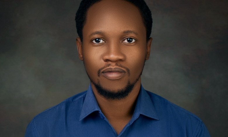 Portrait of a man with a goatee wearing a blue shirt against a mottled background.
